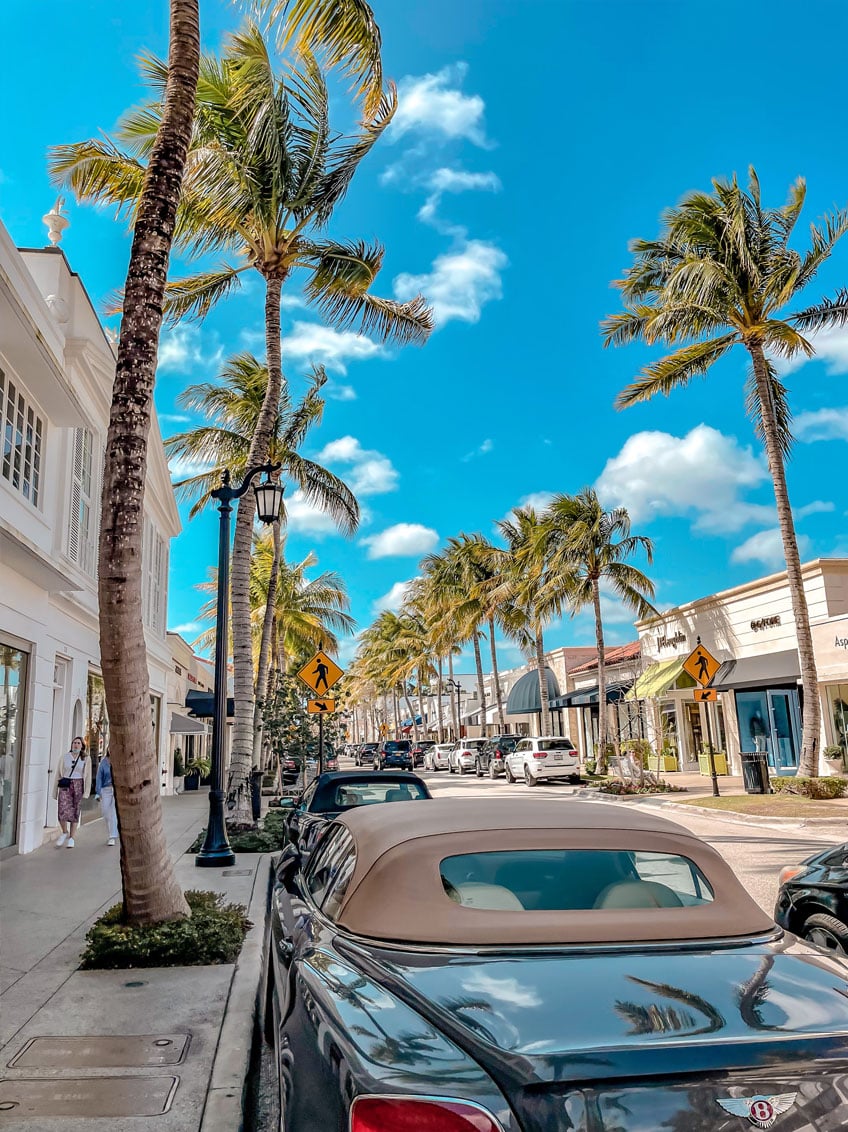 west palm beach street with coconut trees and a vintage car